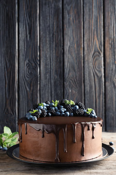 Fresh delicious homemade chocolate cake with berries on table against wooden background