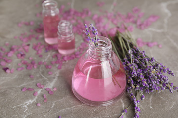 Obraz na płótnie Canvas Bottles with aromatic lavender oil on grey table