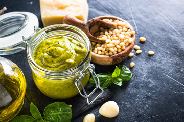 Pesto sauce with ingredients on dark stone table.