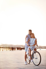 Happy couple riding bicycle outdoors on summer day