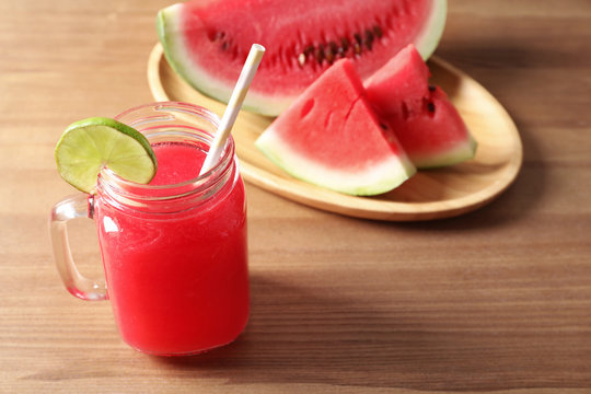 Summer watermelon drink in mason jar and sliced fruit on table