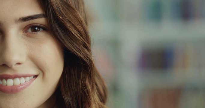 Close up of the young Caucasian good looking woman's half face smiling cheerfully on the blurred background.