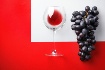 Fresh ripe juicy grapes, glass with red wine and space for text on color background, top view