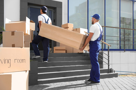 Male Movers Carrying Shelving Unit Into New House