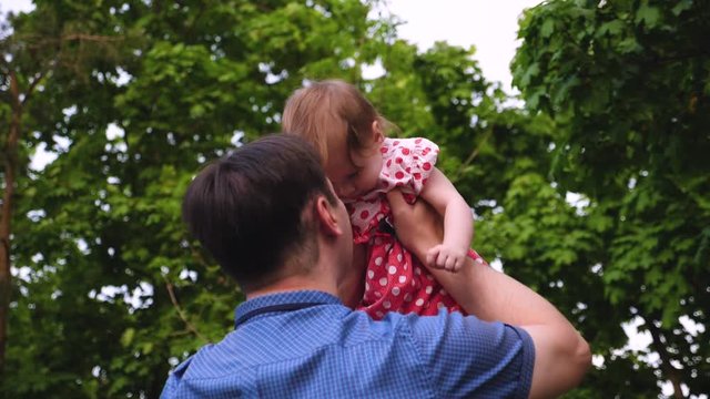 Little girl is jumping in air in hands of dad and laughing. Slow motion.