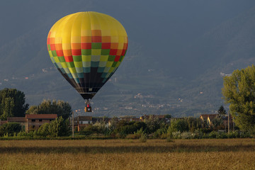 Obraz premium Colorful hot-air balloon flies over typical village in the Tuscan countryside in the light of the sunset