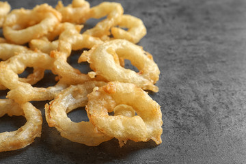 Delicious golden breaded and deep fried crispy onion rings on gray background, closeup
