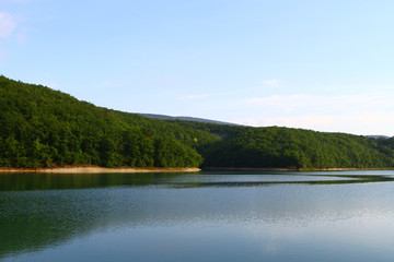 Fototapeta na wymiar Natural landscape photo - wonderful still lake with green hills in distance