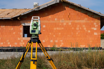 Surveyor measuring equipment (theodolit) on construction site with house in background