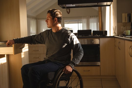 Disabled man removing utensil in kitchen