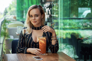 Young pretty woman drinking fresh lemonade at city cafe terrace