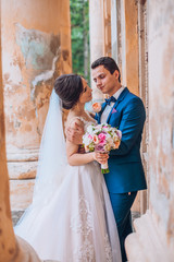 Sensual wedding married couple, valentines hugging in front of old slavic castle. Wedding day of bride and groom. Man and woman posing near old columns. Wedding photoshoot.