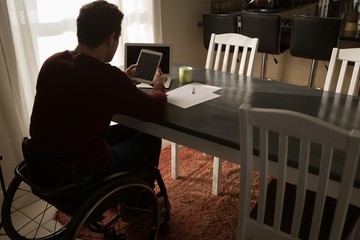 Disabled man using digital tablet on dinning table