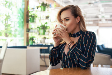 Beautiful woman drinking a cocktail in her hands while sitting a