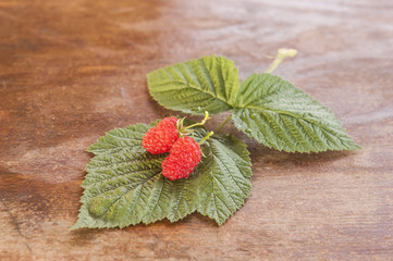 Raspberry with leaves on rustic vintage wooden table
