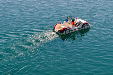 Pedal boat on lake driven by two tourists in summer