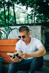 Obraz premium Young hipster man reading a book in the park