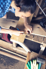 Vertical image of a carpenter woman marks the place of the cut on a wooden Board