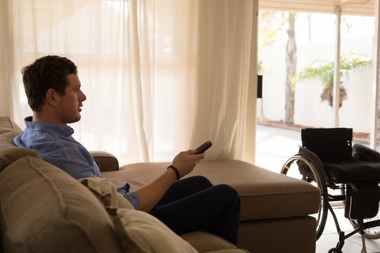 Disabled man changing channels in living room