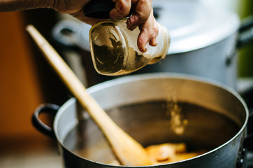 Hand of a woman adding ingredients to the pot where the food is cooking