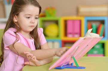 Girl is sitting at the table and reading a book