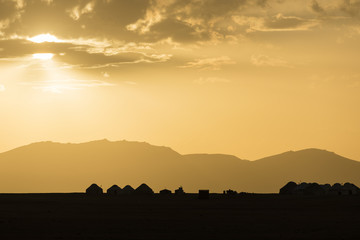 Silhouette of a yurt settlement at Song Kul lake in Kyrgyzstan at sunset