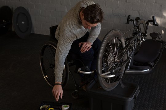 Disabled man repairing wheelchair at workshop