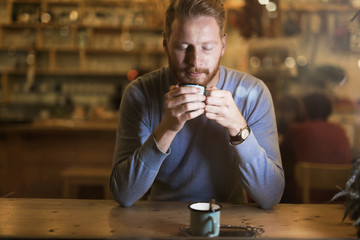 Young handsome man drinking coffee in bar