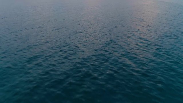 Rapid forward movement aerial shot cycled sea surface high speed flight over ocean or pond top view of calm with shallow ripples and waves pond or ocean or lake sunlight is reflecting in water