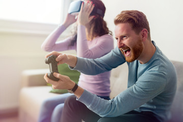 Happy young couple playing video games with virtual reality headsets