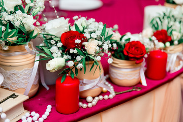 Obraz na płótnie Canvas Dark Red, Marsala, wine red, Bordeaux wedding decor. Peach, light biege, sand color table setting. Candles, white lace jars, bottles, flowers and beads. and white wedding ceremony decor.