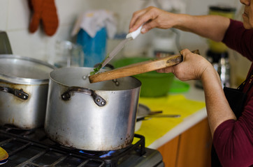Hand of a woman adding ingredients to the pot where the food is cooking
