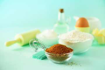 Bakery food frame, cooking concept. Different baking ingredients - butter, sugar, flour, milk, eggs, oil, spoon, rolling pin, brush, whisk over blue background. Copy space.