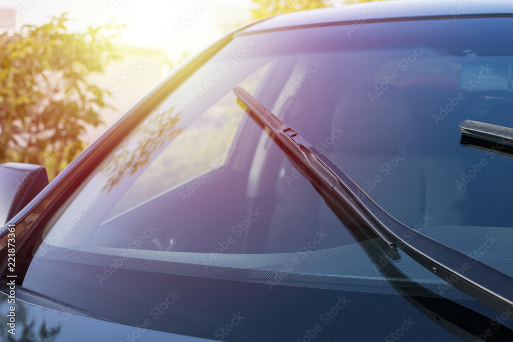 Wall mural Brushes on the car glass with copy space. The work of windshield wipers - brushes and an evening sunbeam