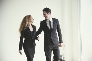 Young businesswoman and businessman with luggage talking in room airport. concept business travel trip.