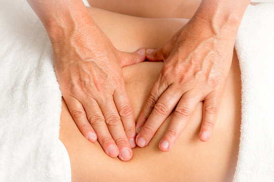 Massage Therapist Gently Massaging a Young Woman's Stomach