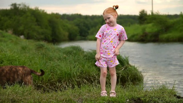 Red-Haired Girl Walking With a Dog on the River. Smile on camera