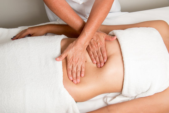 Massage Therapist Gently Massaging a Young Woman's Stomach