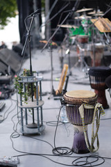 Obraz na płótnie Canvas Djembe, a drum from West Africa, on stage with amplifying equipment before the concert
