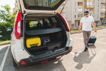 man putting bags in car trunk. ready for car travel