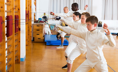 Group practicing fencing techniques in gym