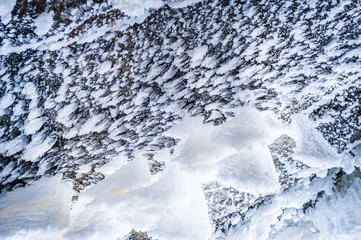 Icicles on cliff. Looking at an ice cave from below. Snow stalactites. Jagala Waterfall, Estonia. Soft focus.
