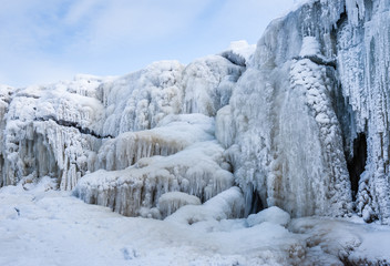 Fototapeta na wymiar A frozen waterfall with ice in blue and white color in winter. Winter background. Jagala Waterfall, Estonia.