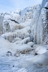 Fototapeta na wymiar A frozen waterfall with ice in blue and white color in winter. Winter background. Jagala Waterfall, Estonia.