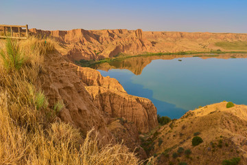 Spectacular red mountain landscape with viewpoint towards a calm lake and vegetation in the background in the Barrancas de Burujon, Toledo, Spain