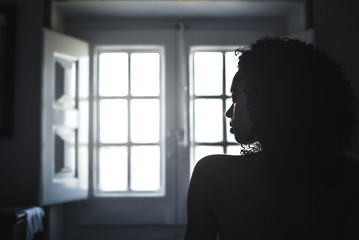 Woman wrapped in a towel looking by a vintage window.