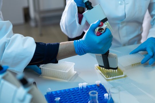 Female scientists using pipette in laboratory