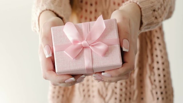 girl holding a present in a pink gift box. female surprise. congratulation celebration reward and gratitude concept.