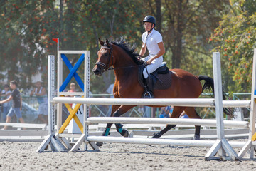 Young man riding horse on show jumping event. Sportsman on his course in equestrian competition