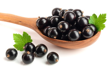 black currant with leaf in wooden spoon isolated on white background
